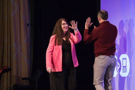 Two Level Access employees about to exchange a high-five as they pass each other on stage.